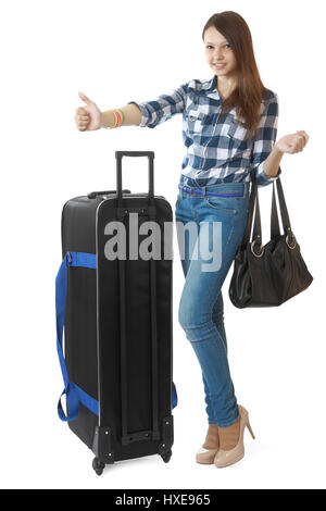 Teen girl 16 years old, with a big, black travel bag on wheels. Girl hitchhiking. Girl 16 years old in jeans and a plaid shirt, hitchhiking or taxi st Stock Photo