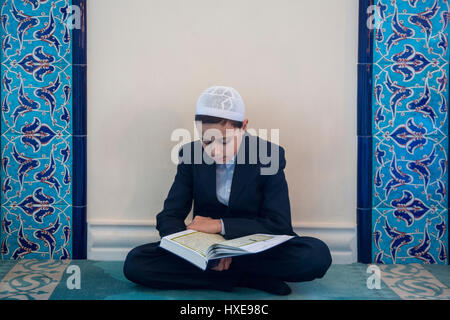 A boy reading the Koran holy book at the annual Koran festival in the Moscow Cathedral Mosque, Russia Stock Photo