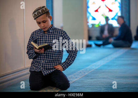 A boy reading the Koran holy book at the annual Koran festival in the Moscow Cathedral Mosque, Russia Stock Photo