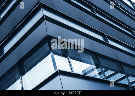 Corner of modern building facade, abstract fragment, shiny windows in steel structure, blue toned photo background Stock Photo