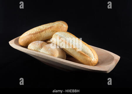 Mini French Baguettes on a rectangular wood bowl with black background Stock Photo