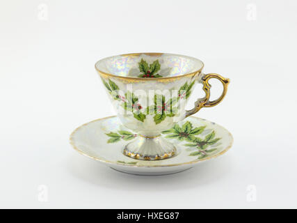 Tea cup and saucer with Christmas holly printed isolated on white background Stock Photo