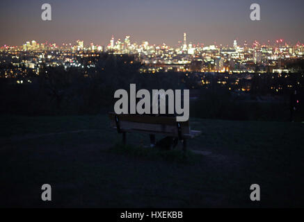 People looking at a view of the London skyline at night from Parliament Hill, Hampstead Heath, north London. Stock Photo