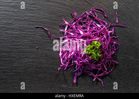 top down of finely chopped red cabbage decorated parsley on black slate stone background, concept raw food, copy space Stock Photo