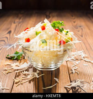 concept of vegetarian food with white cabbage in bowl decorated red pepper and cucumber, close up, copy space Stock Photo