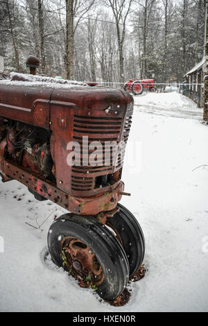 Rusted red tractor in the snow on a New England farm Stock Photo