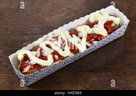 traditional Dutch frikandel special in a cardboard container on wooden background Stock Photo