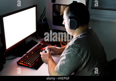 Man playing computer game on custom made desktop with joypad, keyboard, mouse. Stock Photo