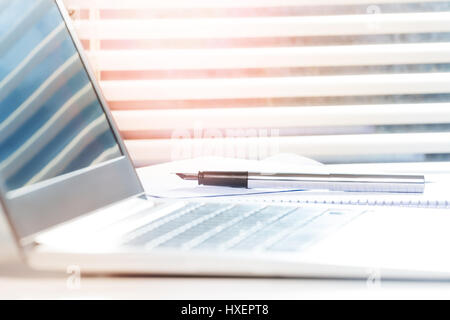 Picture of working place with opened laptop and metallic fountain pen on the desk Stock Photo