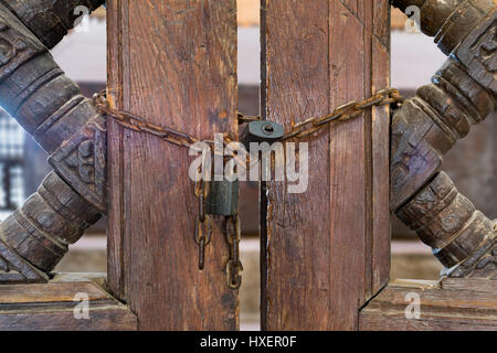 Old rusted padlocks and rusted chain on a half closed wooden interleaved double door Stock Photo