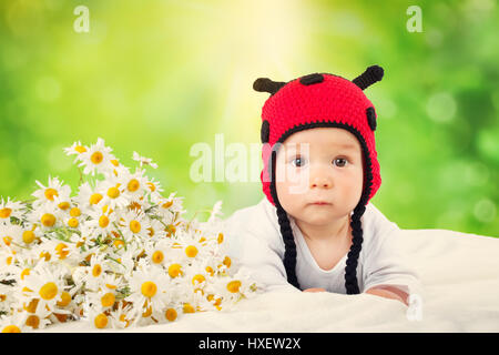 Cute baby lying in the bed on white blanket in ladybug hat Stock Photo