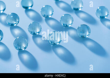 Clear glass marbles on a white surface bathed in a blue light Stock Photo