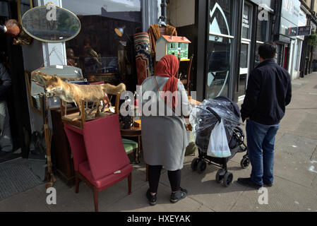 Asian family refugee dressed Hijab scarf  on street in the UK everyday scene junk shop or antique shop fox Stock Photo