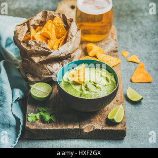 Fresh guacamole sauce in blue ceramic bowl, corn chips, beer Stock Photo