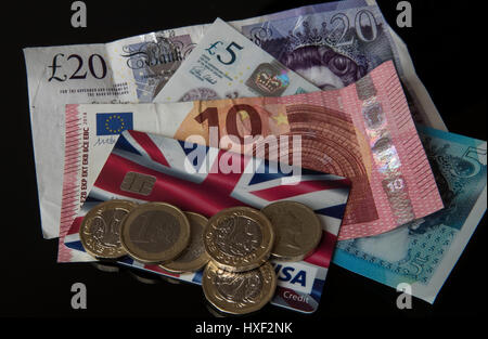 New 12-sided £1 and 1 Euro coins on a credit card with a new £5 note, £20 note, 10 Euro note in Liverpool as the new pound coin entered circulation - with early teething problems expected at coin-operated machines across the country. Stock Photo