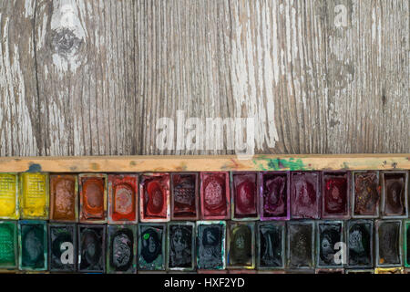 Box with watercolors and brushes on wooden surface Stock Photo