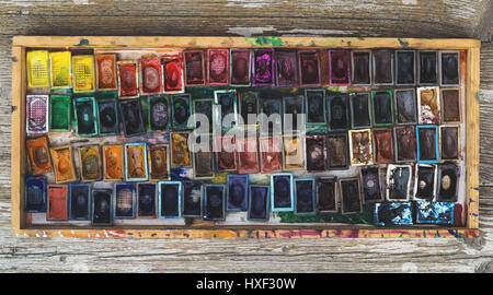 Box with watercolors and brushes on wooden surface Stock Photo