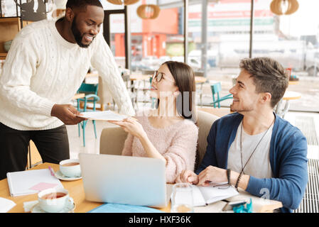 Young guy giving papers to his fellow students Stock Photo