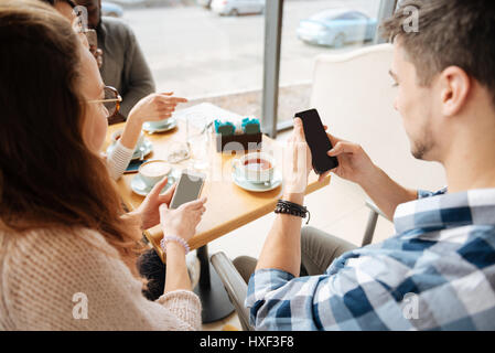 Positive friends using smartphones in tha cafe Stock Photo