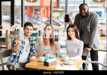 Youngsters with smartphones resting in the cafe Stock Photo
