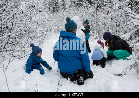 Family making snowman on beautiful snowy day Stock Photo