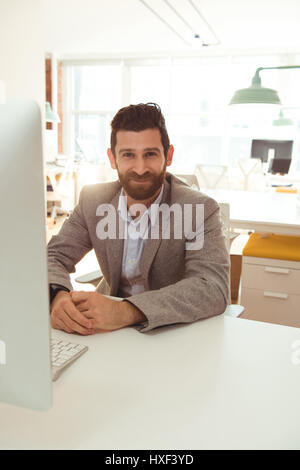 Portrait of businessman sitting at desk in office Stock Photo