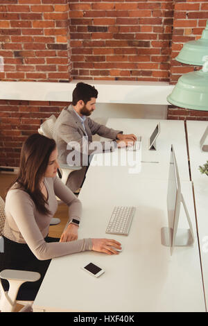 Businessman and his colleague working at desk in office Stock Photo