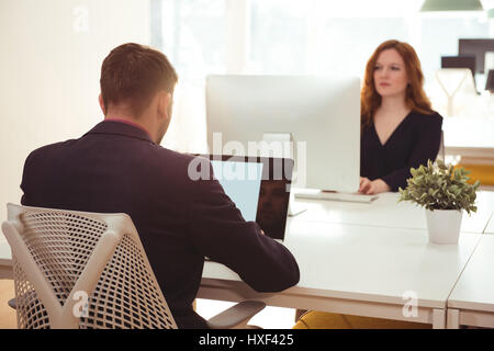 Businessman and his colleague working at desk in office Stock Photo