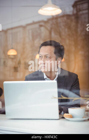 Thoughtful businessman using laptop in coffee shop Stock Photo