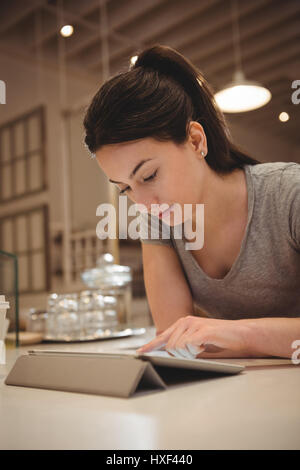 Young female barista using tablet computer in coffee shop Stock Photo
