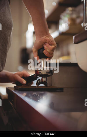 Cropped image of female barista tamping coffee in cafe Stock Photo