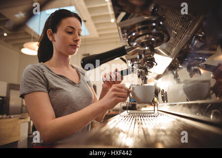 Young female barista making espresso in coffee shop Stock Photo