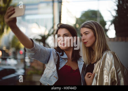 Happy friends taking selfie on mobile phone Stock Photo