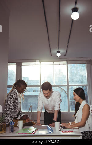 Group of executives discussing over digital tablet at office Stock Photo