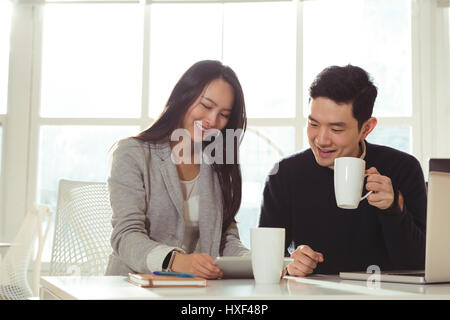 Male and Female executives discussing over digital tablet at desk in office Stock Photo