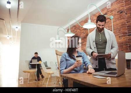 Male and female executives discussing over digital tablet at desk in office Stock Photo