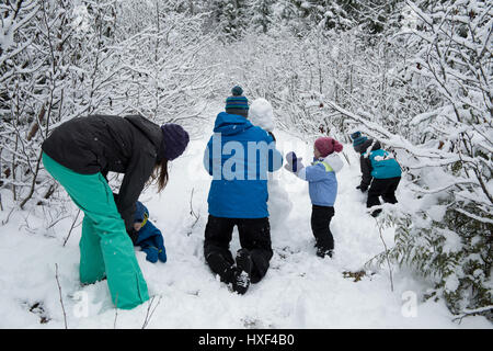 Parents and children making snowman on beautiful snowy day Stock Photo