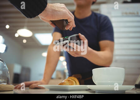 Customer making contactless payment with smartphone in coffee shop Stock Photo