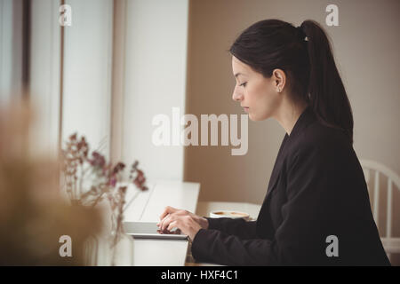 Side view of businesswoman using tablet computer in coffee shop Stock Photo