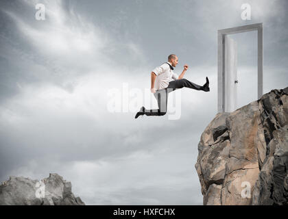 Businessman jumping over the mountains to reach a door Stock Photo