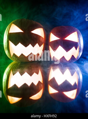 Two glowing pumpkins for Halloween on blue and green light Stock Photo