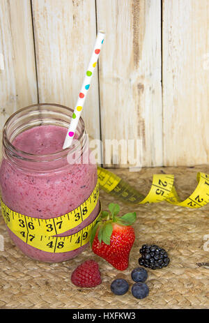 pink berry smoothie in mason jar with polka dot straw and yellow tape measure