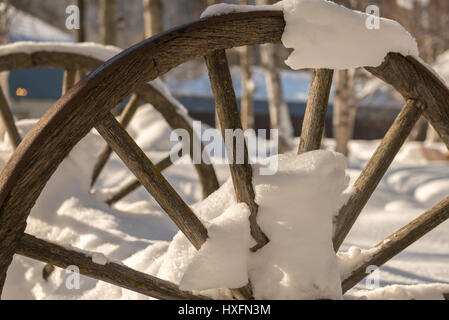 Antique Wagon wheel mostly buried in snow at Chena Hot Springs resort, near Fairbanks, Alaska Stock Photo