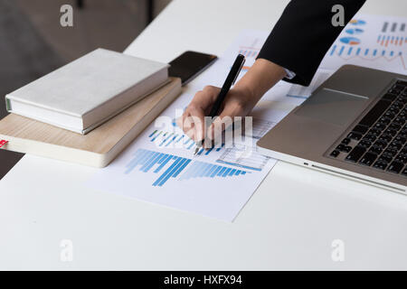 Working woman hand holding pen with Business summary or Business plan report with Charts and graphs in Business concept Stock Photo