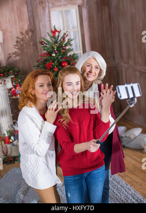 Happy family of three generations making selfie in front of decorated for Christmas fireplace Stock Photo