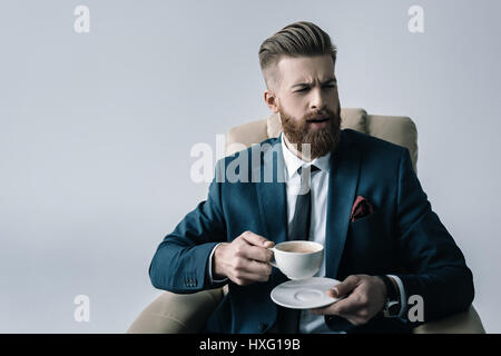 portrait of elegant businessman holding cup of coffee on grey Stock Photo