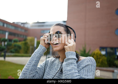 Happy young woman listening music outdoor by headphones Stock Photo