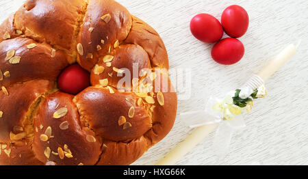 Traditional Easter bread ,tsoureki with a red egg in the middle , tree red eggs and an Easter candle beside Stock Photo