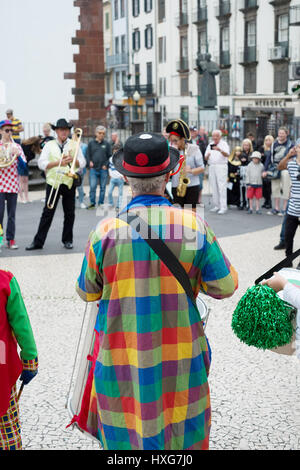 A musician in a  multi coloured coat playing in a street band in Funchal, Madeira Stock Photo