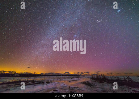 Frozen Lake Huron shoreline near Tobermory in winter with snow around the limestone alvar rocks.  Night with the milky way and stars reflecting and li Stock Photo